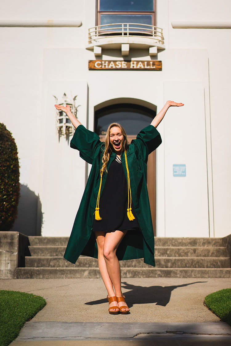 Cal Poly grad in gown in front of building