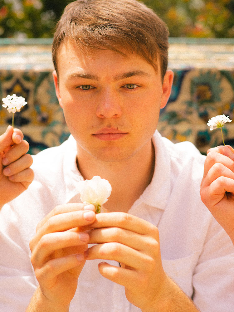 Man in white button-up shirt surrounded by white flowers